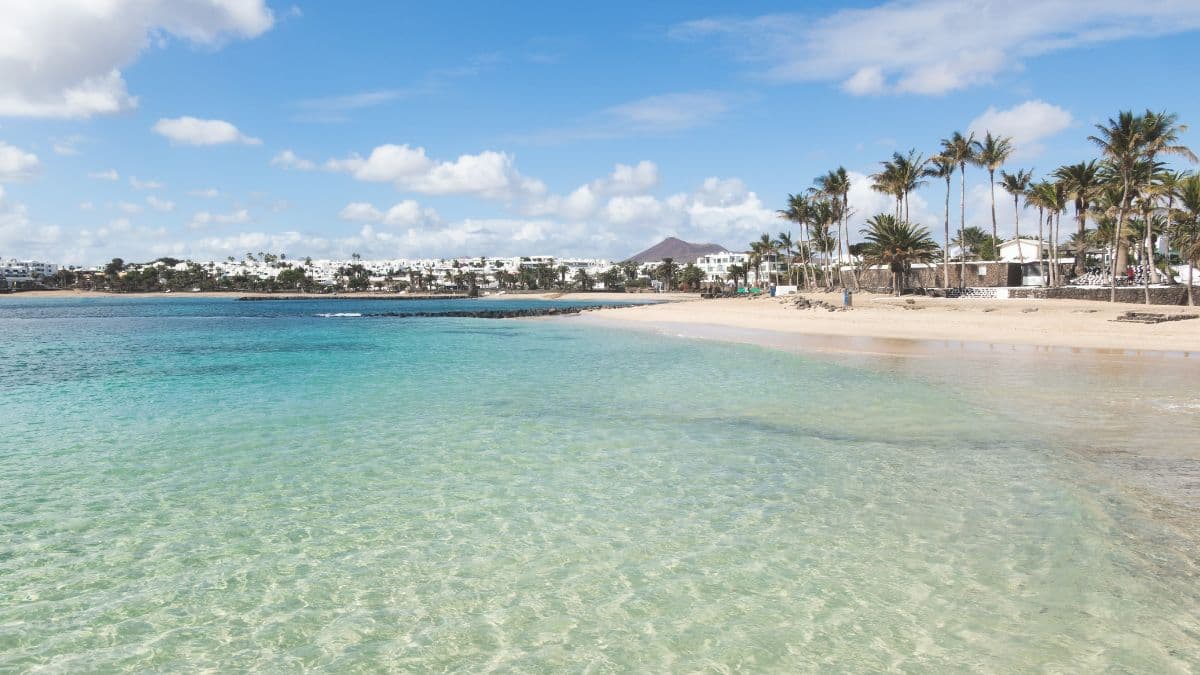 Clear blue water on the white sandy beach in Costa Teguise Lanzarote